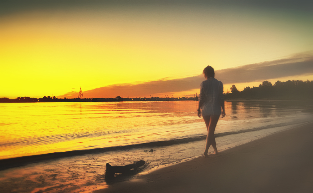 Расскрепощеная красотуля на пляже провожает закат солнца