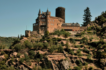 Прогулка по Рейну / Замок Катц (нем.Burg Katz) стоит на выступе скалы на берегу реки в прекрасной Долине Среднего Рейна. Из окон и со стен замка открывает завораживающий вид на окрестности и прекрасную долину Рейна, внесенную Юнеско в список Всемирного наследия. Недалеко от замка Катц находится его собрат, замок Маус (нем.Burg Maus), а на противоположном берегу расположены руины крепости Райнфельс (нем.Burg Rheinfels). Замок Катц был построен около 1371 года по распоряжению графа Вильгельма II Катценельнбогена (нем.Wilhelm II Katzenelnbogen), который назвал его своим именем – Катценельнбоген. Это название показалось народу слишком трудным и замок стали называть Катц (Кошка).