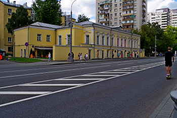 Таганская улица / Таганская улица в Москве. Главный дом городской усадьбы Г.И. Крюкова — Стариковых — Н.Ф. Ильина (2-я половина XVIII века; XIX век, архитектор В.Я. Яковлев). Необычно вытянутое здание, окружённое каменной оградой с пилонами, сохранилось со времен старой каменной Москвы, когда при оформлении городских сооружений пользовалась популярностью резьба из камня. Особняк принадлежал известным в Москве личностям: Г.И. Крюкову, семье Стариковых, затем Н.Ф. Ильину. В XXI веке здание занимают различные коммерческие организации. Август 2023.