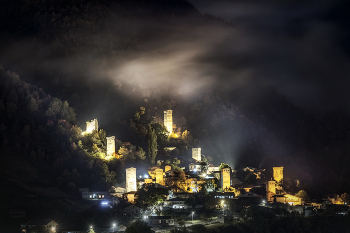 Mestia Towers In Autumn Nigh / Башни Местии в октябрьской ночи. Прожектора подсвечивают башни и пролетающие низкие облака.