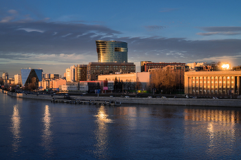 Золото заката в отражениях Невы. / Санкт-Петербург. Вечер. Закат. Вид с моста Александра Невского на Малоохтинскую набережную..