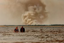 ПЕКЛО 2010 / Жаркий июльский день на Волге, люди ищут спасения в воде. На другом берегу уже полыхает очередной пожар.