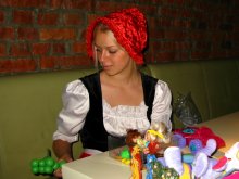 В ожидании... / Девушка в национальном костюме играет с детьми, пока их родители заняты приемом пищи.