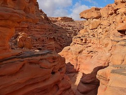 Цветной каньон / Около 5 миллионов лет стихиям понадобилось для создания каньона посреди песка и каменистой почвы. Все началось с крупного землетрясения, вследствие которого в скале появилась глубокая трещина длинной в 5 километров. Миллионы лет трещину вымывали долгожданные в пустыне дожди, обдували ветра, и сегодня люди могут наблюдать плавные линии ущелья в самом прекрасном его виде. Несмотря на жару вокруг, в извилистом ущелье сохраняется прохладная температура. В некоторых местах ширина между стенками трещины составляет 30 сантиметров, но в среднем ширина прохода — около 1 метра. Преодолевая путь в 5 километров по дну каньона, можно любоваться красивым цветом гладких стен: от белого, желтого, красного до коричневого и шоколадного. Стенки скалы — это твердая каменистая почва с вкраплением кораллов. Это обозначает, что когда-то очень давно часть Синайского полуострова была под водой. Виды небольших пещерок и скал в каньоне разбудят фантазии любого человека. В некоторых из них можно увидеть изумительные картины заката и рассвета, замки, колонны и статуи, словом, всё, что только подскажет воображение.