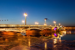Благовещенский мост / Мост Лейтенанта Шмидта стал первым мостом Санкт-Петербурга. В своей истории мост несколько раз проходил реконструкцию. Самая масштабная произошла в 1930 – е годы, когда существенно расширили проезжую часть, а разводная опора перешла в центр моста.
Изначально мост был назван Невским, позже переименован в Благовещенский мост (название происходило от Благовещенской площади, располагавшейся на левом берегу), с 1855 г. строение получило имя Николаевского Моста. В 1917 г. после революции мост вновь был переименован и название Мост Лейтенанта Шмидта сохранилось до начала XXI в., после чего мосту вернули прежнее историческое название.