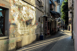 Странный свет / Сербия. Город Нови Сад. Меня заинтересовало граффити. Сфотографировала. Рассмотрев дома, подивилась странному свету освещающему эту стену. Ведь солнце находится слева, судя по теням исходящим от людей в переулке.