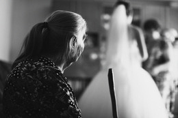 Смена поколений / Мама сидя на стуле и держа трость в руке смотрит на то как ее дочь одевает свадебное платье на ее внучку