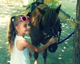 Девочка и лошадь / Солнечный день в парке. Детская площадка, место для катания на пони.