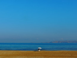 Зонтик на пляже острова Крит / Одинокий пляжный зонтик на берегу Средиземного моря. Греция, Крит.