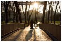 на мосту / человек  с коляской на мосту в лучах заходящего солнца