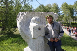 Репортажный портрет / Участник фольклорного праздника подле садово-парковой скульптуры в парке на берегу пруда.