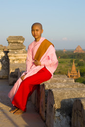 Молодая бирманская девушка-монашка сидит на парапете древнего буддистского храма. Баган, Бирма / Молодая бирманская девушка-монашка сидит на парапете древнего буддистского храма. Баган, Бирма
