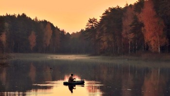 Осенним вечером на озере / Осенним вечером на озере рыбак на лодке ловит рыбу