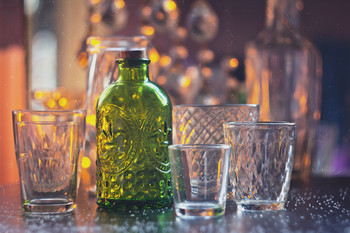 Зеленая бутылка / Бутылка из зеленого стекла в окружении прозрачных стаканчиков