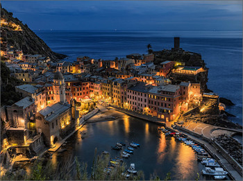 Vernazza bei Nacht / Vernazza is one of the 5 centuries-old villages of the Cinque Terre on the rugged Ligurian coast of north-western Italy. The small marina of the village is surrounded by colorful houses. The church of Santa Margherita di Antiochia has a bell tower with dome. The medieval Doria rock castle with a cylindrical tower once served as a defense; directly below lies the bastion Belforte.