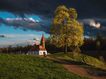 Before the storm / Bright dramatic landscape with views of the old castle at sunset and a man walking with a stroller in front of a thunderstorm. Gatchina. Russia.