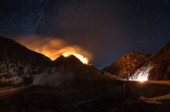 Лесной пожар в горах / Ночная панорама в горах Северной Осетии. Под звёздным тёмно-синем небом, на вершине одной из гор, полыхал оранжевый пожар, который освещал красным светом дорогу и соседние скалы. Было очень жалко сосновый лес! 
4 января, 2021 года.
Из фотопроекта «Кавказ без границ».