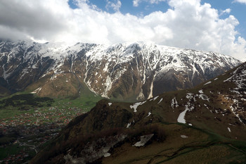 В горах Северного Кавказа в начале мая. / горы снег селение облака