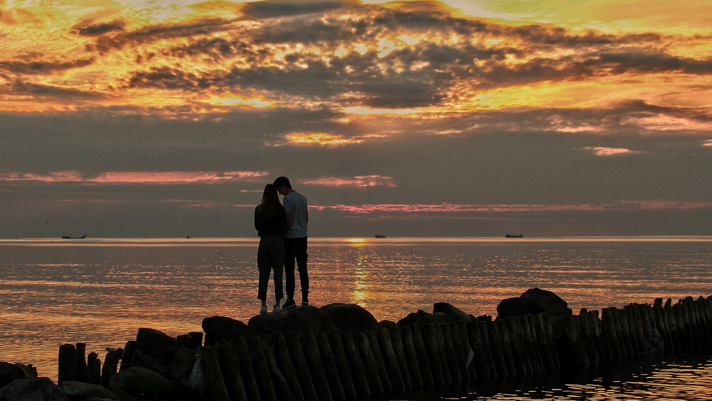 Пара встречает закат на берегу моря